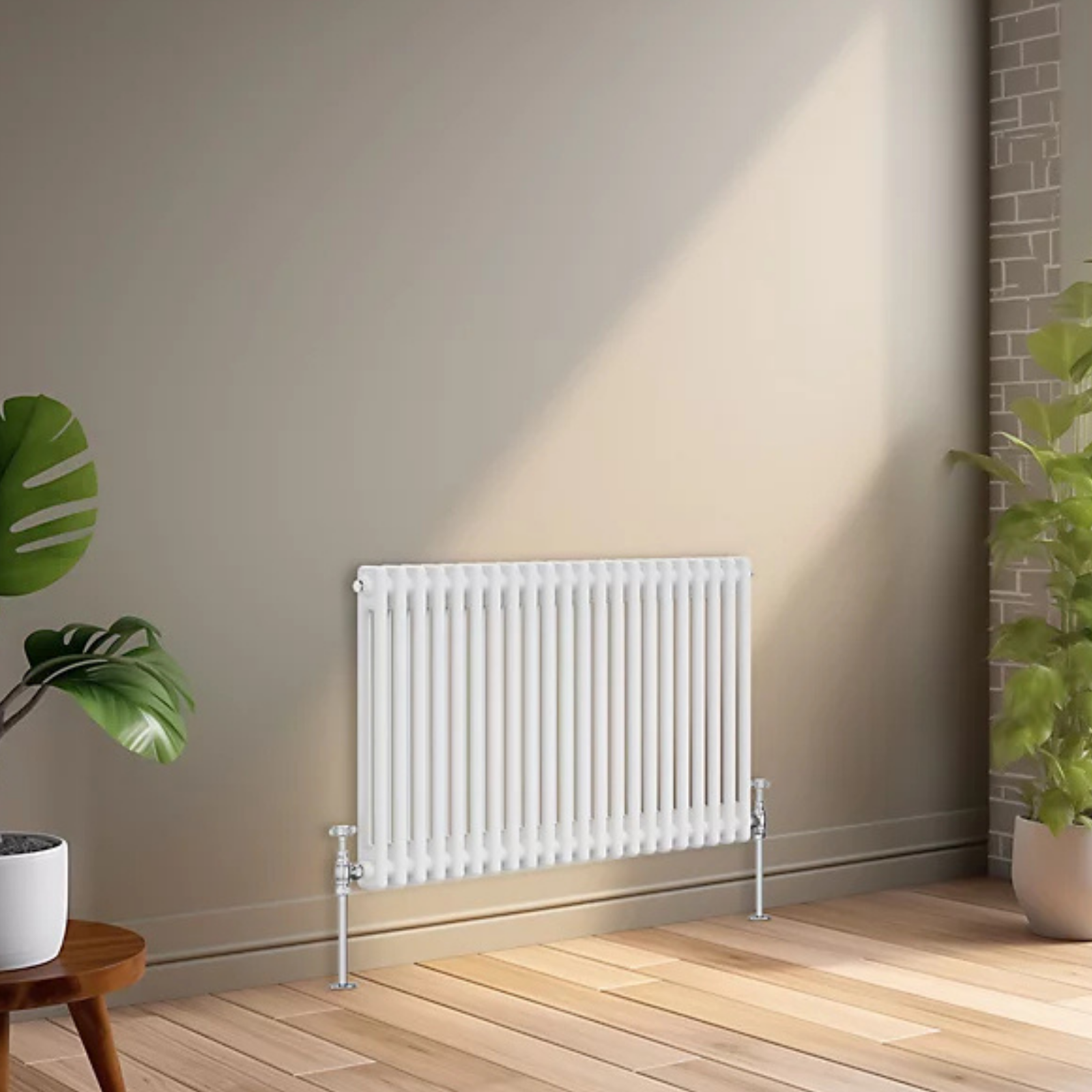 A white panel radiator mounted on a beige wall in a modern room with light wood flooring, a potted green plant on the left, and a brick column on the right.