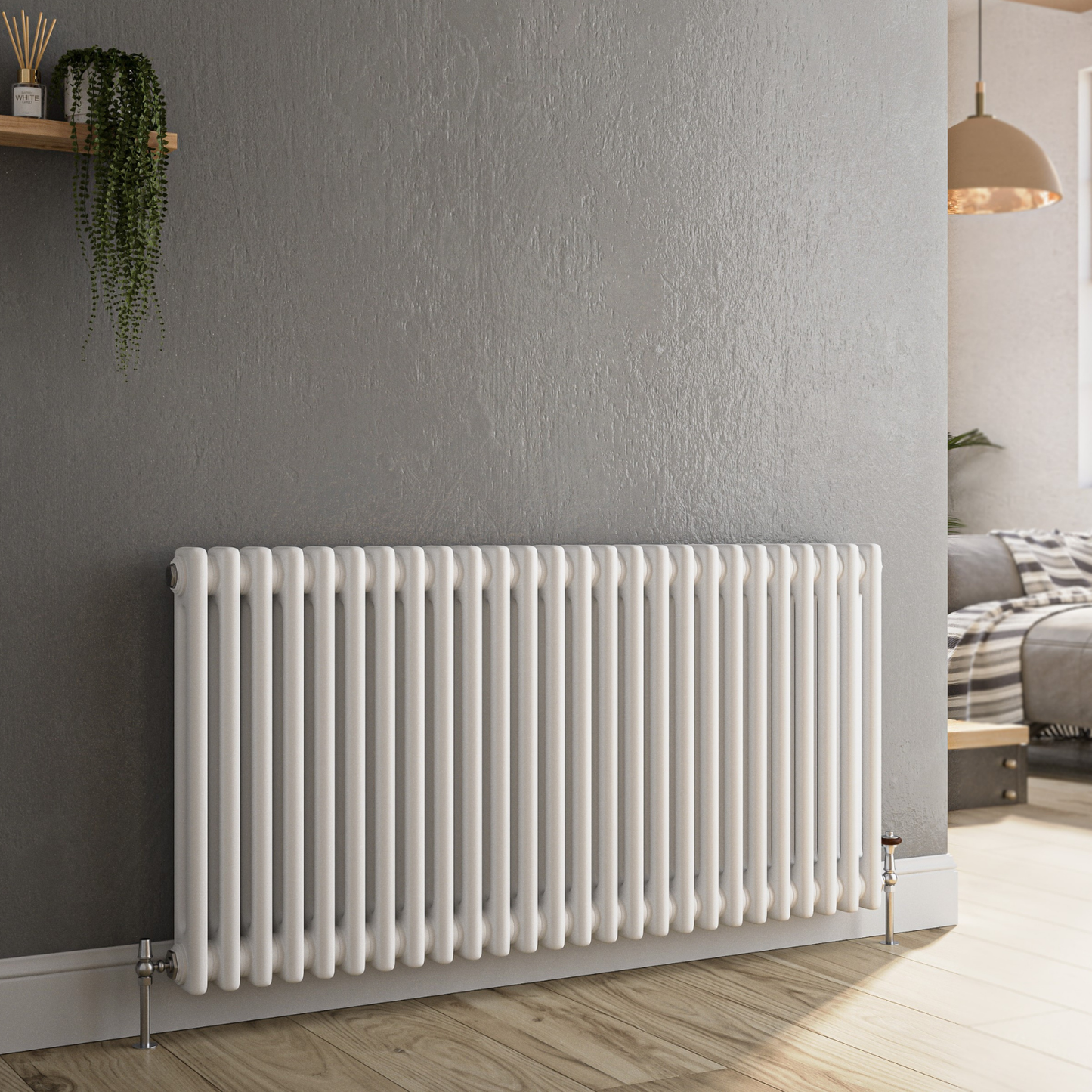 A white cast iron column radiator mounted on a textured gray wall in a modern room with light wood floors and a bed visible in the background.