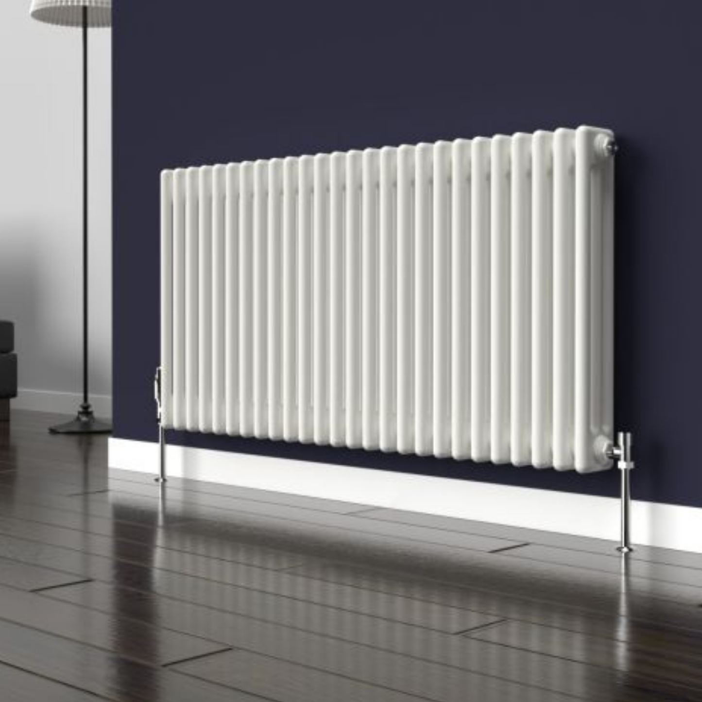 A white cast iron radiator with vertical bars, mounted on a dark navy blue wall above a white baseboard and dark wood floor.